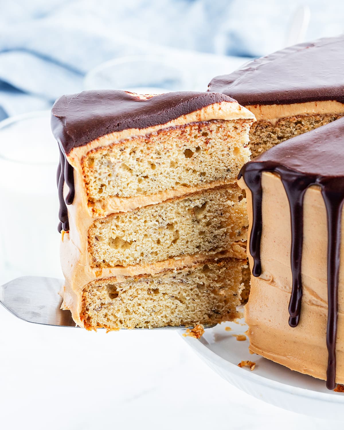 A slice of triple layer banana cake on a spatula being pulled out of the cake.