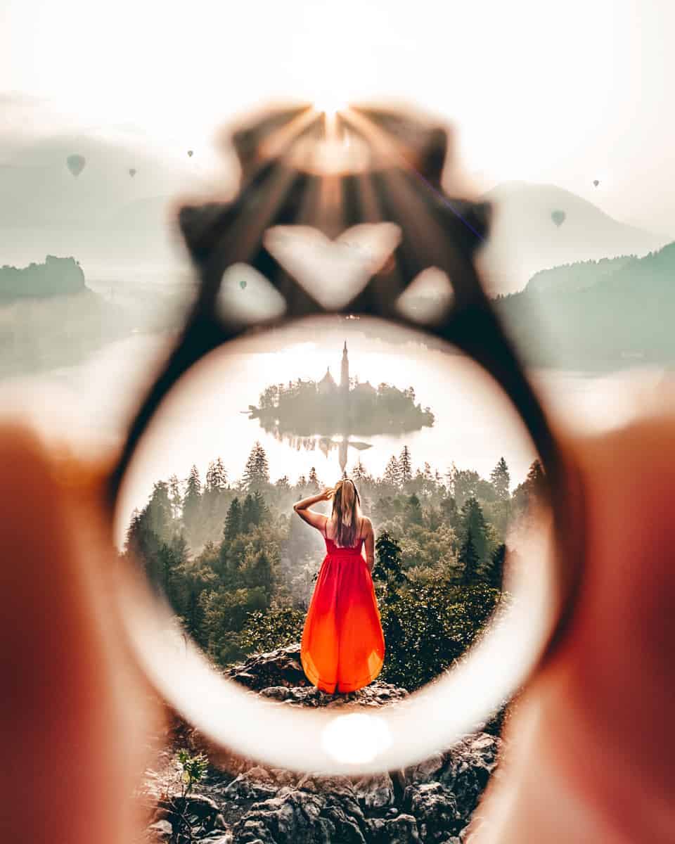 Girl in red dress overlooking Lake Bled framed through a wedding ring. 