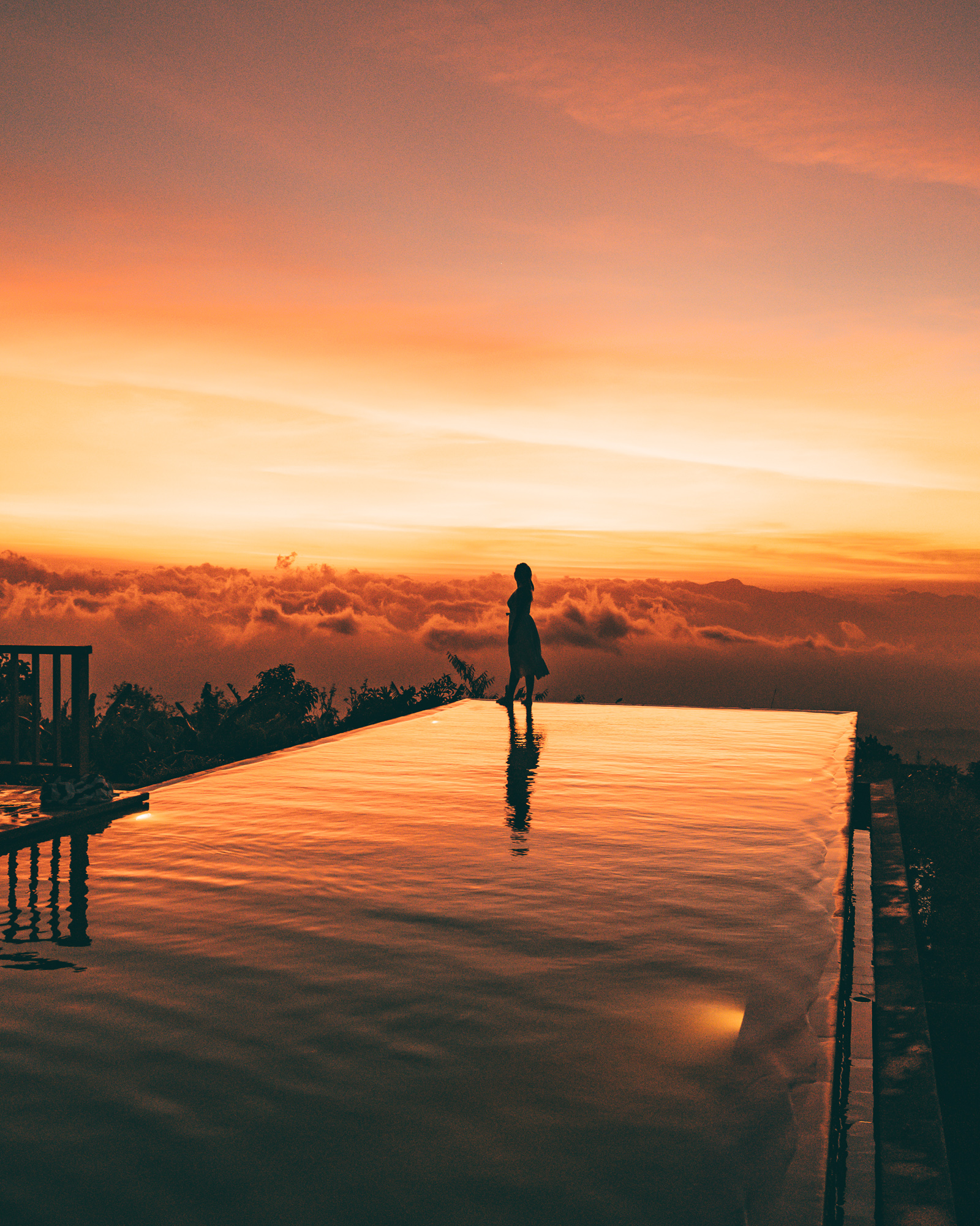 Kylie walking along an infinity pool with a crazy orange and red sky in the background, showing the quality of images with the Sony A7Riii