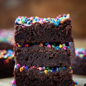 Stacked Rainbow Chip Brownies on a wooden table.