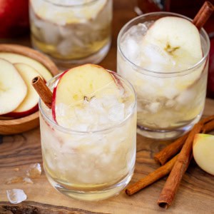 Glasses of Apple Bourbon Milk Punch on a wooden cutting board.