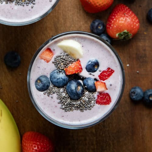 Looking down on the top of High Protein Berry Bliss Smoothie glasses on a wooden table.