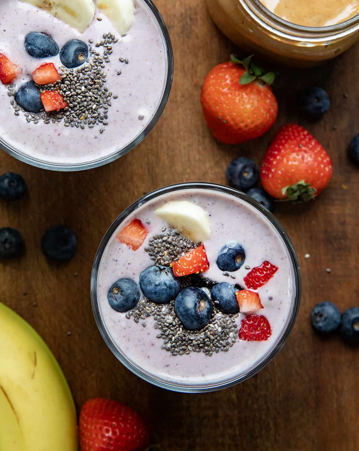 Looking down on the top of High Protein Berry Bliss Smoothie glasses on a wooden table.