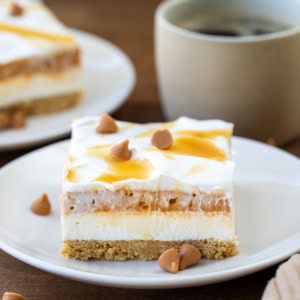 Pieces of Butterscotch Delight on white plates on a wooden table.