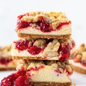 Stack of Cherry Almond Cheesecake Bars on a white table close up.