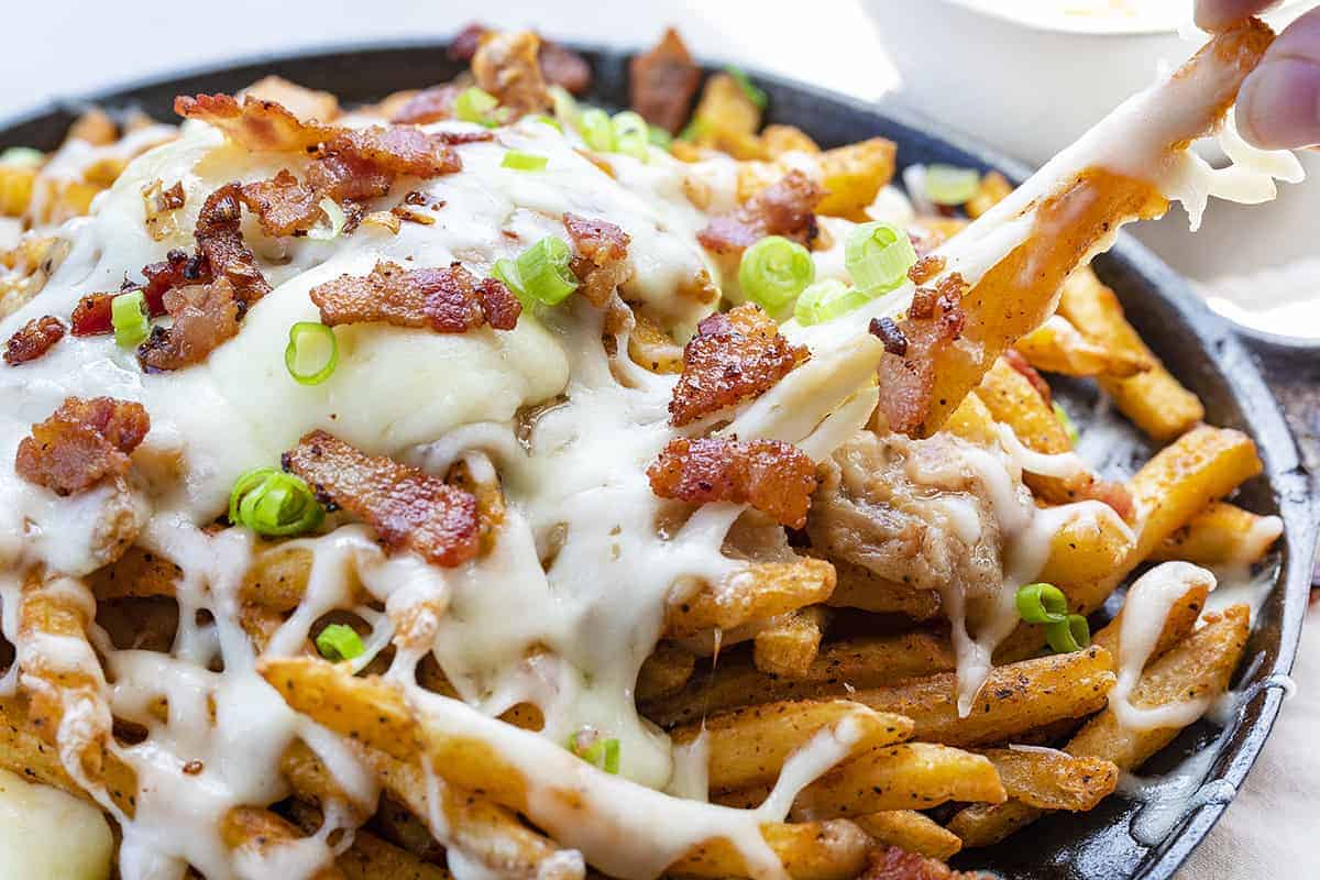 Pulling a French Fry from a Poutine Skillet Cheese is Stretching