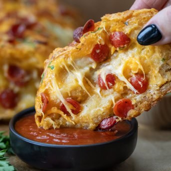 Piece of Pepperoni Pull Apart Bread being dipped into sauce.