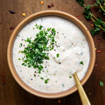 Bowl of Cowboy Butter Ranch Dressing on a wooden table from overhead.