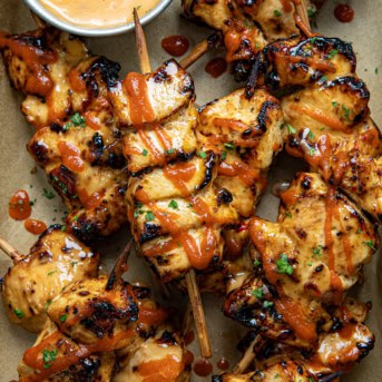 Chipotle Bang Bang Chicken Skewers in a tray with Bang Bang Sauce from overhead.