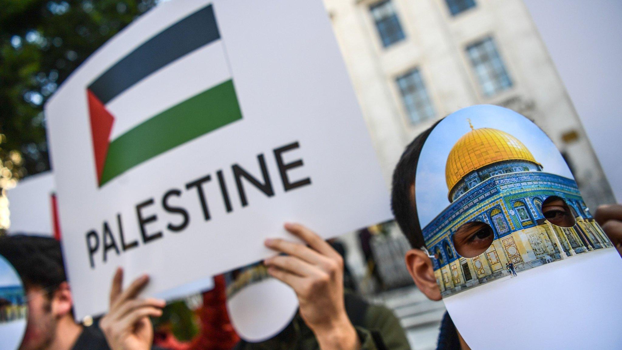 People wearing masks featuring Jerusalem's Dome of the Rock mosque gather outside the Organisation of Islamic Co-operation summit in Istanbul (13 December 2017)