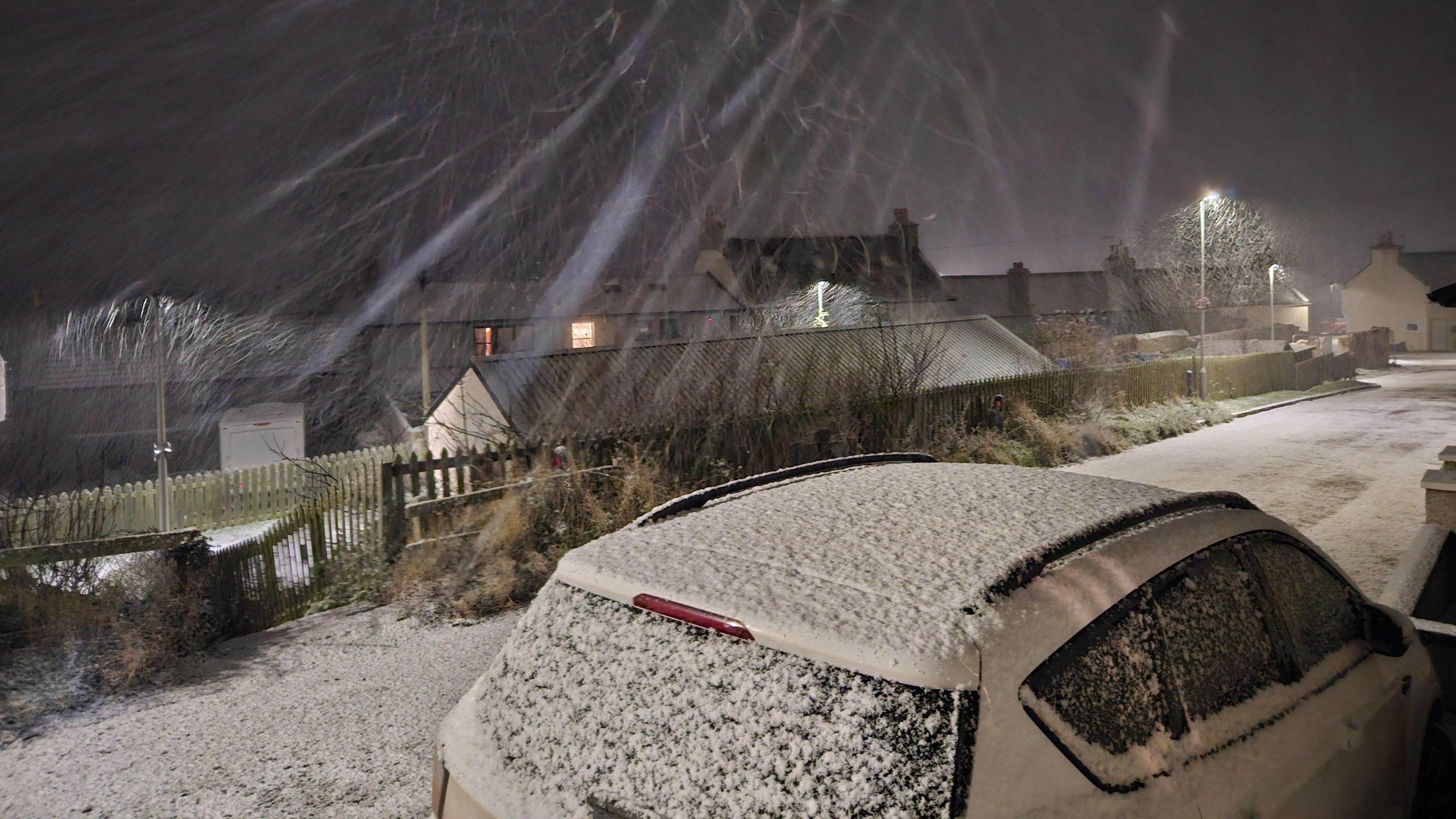 Streaks of snow falling caught on camera, as it covers a car and the ground