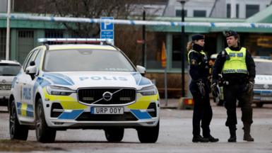 Swedish police officers stand next to a police car