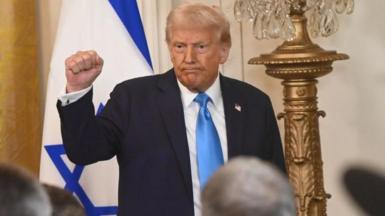 President Donald Trump puts his fist into the air following a joint press conference with Israeli Prime Minister Benjamin Netanyahu (not seen) at the White House 