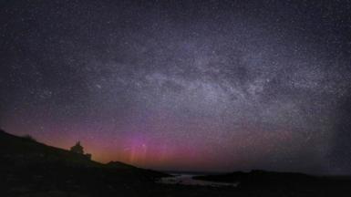 An expanse of night sky over a rural landscape, showing the Northern Lights, the Milky Way and a meteor 