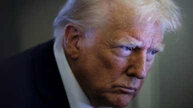 US President Donald Trump looks on as reporters ask questions aboard Air Force One during a flight from Las Vegas, Nevada, to Miami