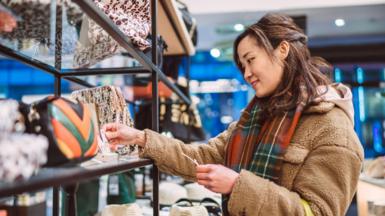 Woman looks at price of handbag while shopping in a store