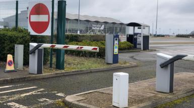 A car park barrier at the entrance to Doncaster Sheffield Airport. The terminal building stands in the distance. 