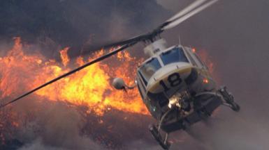 A helicopter dropping water on a fire from above