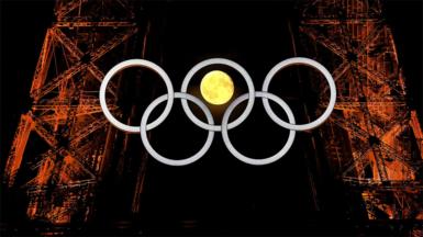 A full moon can be seen through the central ring of the Olympic Rings as they hang from the Eiffel Tower