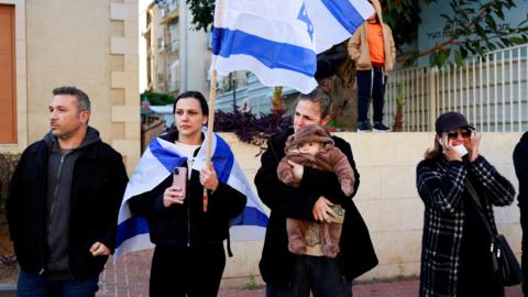 Israelis react as they gather in Rishon LeZion, central Israel, to watch the funeral procession for Shiri, Kfir and Ariel Bibas, who Israel says were killed in captivity after being taken hostage during Hamas's 7 October 2023 attack on southern Israel (26 February 2025)