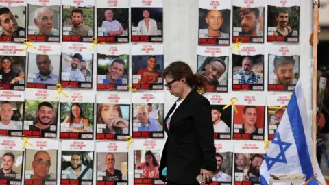 A woman walks past a display of posters calling for the release of Israeli hostage