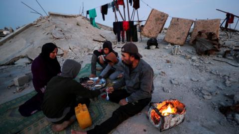 A Palestinian family break their fast during the Islamic holy month of Ramadan, on the rubble of their house in Jabalia refugee camp, northern Gaza (2 March 2025)