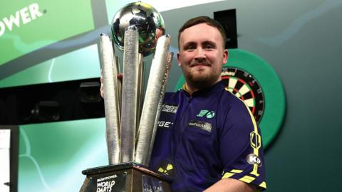 Luke Littler lifts the PDC World Darts Championship trophy at Alexandra Palace