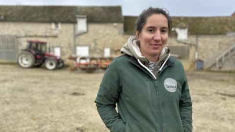 French farmer Alix Heurtault stands on her farm with a tractor in the background