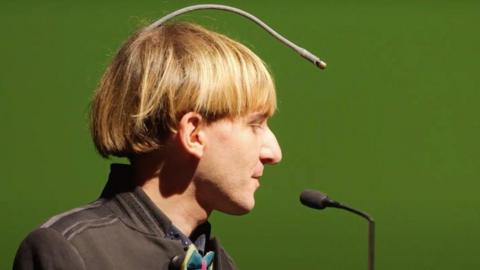 Neil Harbisson side view of him and his antenna, which starts at the back of his head and goes in an arc to above his forehead