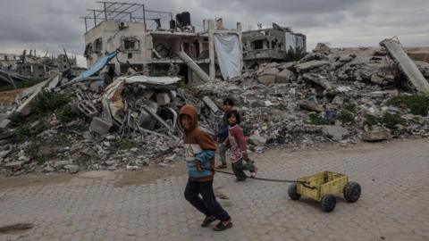 Palestinian children walk past destroyed buildings and makeshift shelters in Beit Lahia, northern Gaza 