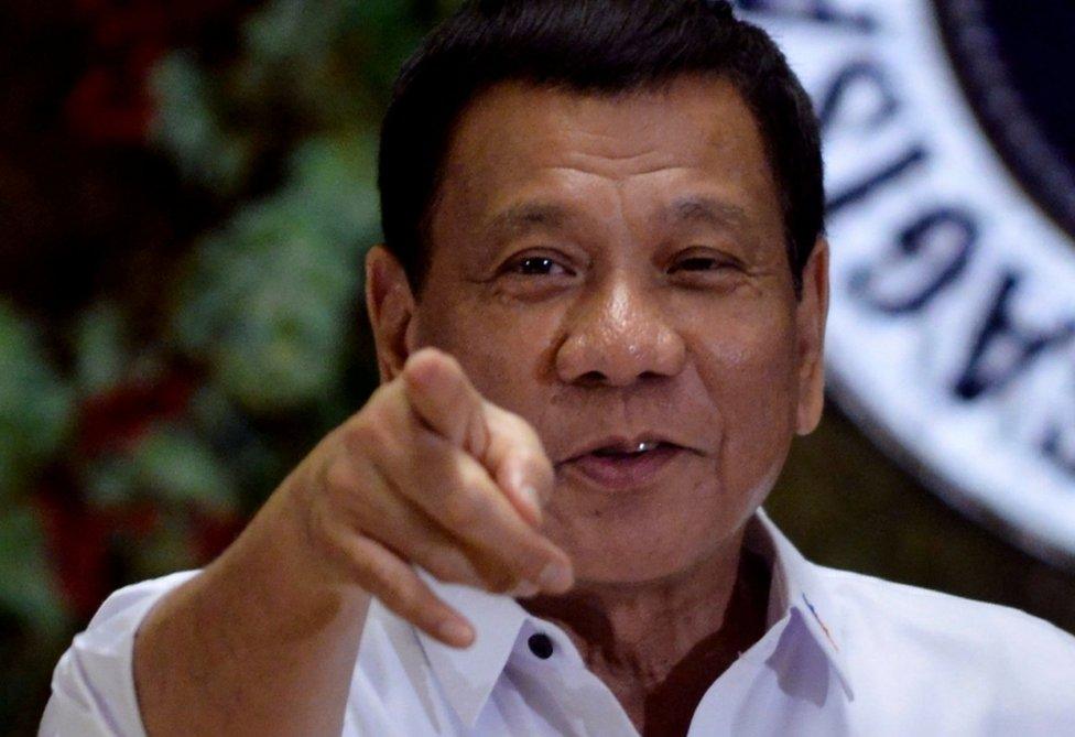 Philippine President Rodrigo Duterte points to photographers during an awarding ceremony for outstanding government workers, at the Malacanang Palace in Manila.