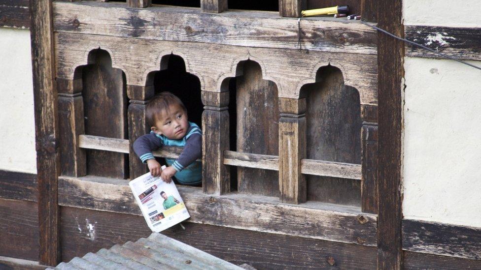 A young boy holds a newspaper