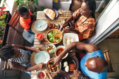 Vue aérienne sur une famille dînant sur un balcon avec un barbecue, des brochettes végétariennes et de la nourriture africaine traditionnelle.