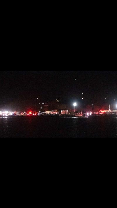 Emergency vehicles gathered on the banks of the Potomac at night time