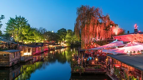 Colourfully lit buildings along a river in Berlin (Credit: Alamy)