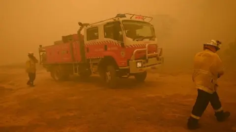 AFP Firefighters protect a property from bushfires burning near the town of Bumbalong south of Canberra