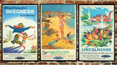 Three posters side by side: the jolly fisherman to the left, one in the middle advertises Mablethorpe and Sutton on Sea, and features a slim lady in a striped bikini on the sand while children play nearby.  The third one says "Lincolnshire: visit the bulb fields in April and May".