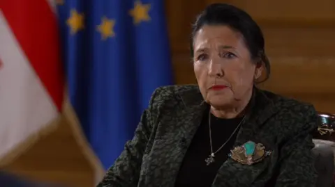 Georgia president Salome Zourabichivili looking into camera. The EU and Georgia flags can be seen in the background