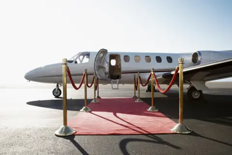 Red carpet leading to a private aircraft - stock photo