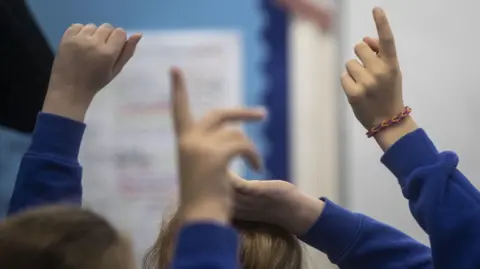 A generic image of pupils hands in the air answering a question