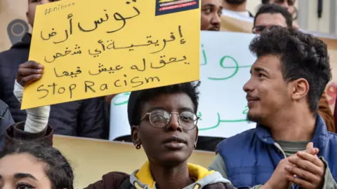 Getty Images A person is holding a sign during a demonstration in Tunis to protest against racism and against President Saied latest comments about the urgency to tackle illegal immigration in the country.