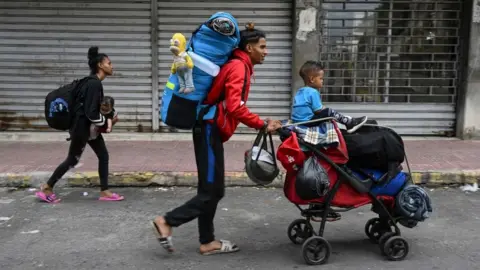 Getty Images A Venezuelan family heads to the Temporary Housing Center for Migrants San Antonio Casa Esperanza after walking for weeks in order to cross into Colombia and continue their journey to the United States, in San Antonio del Tachira, Venezuela, on September 25, 2022.