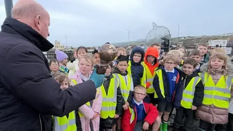 Bill Dale showing the Energy Globe award to pupils