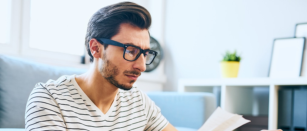 Casual man paying bills at home with laptop