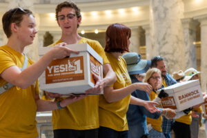 A line of supporters of the Idahoans for Open Primaries — many wearing mustard yellow t-shirts — pass signatures for the ballot initiative to turn into the Idaho Secretary of State’s Office.