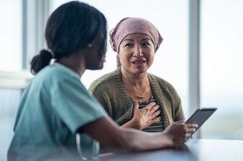 Breast Cancer. A doctor examines a woman who is holding her hand over her breast.