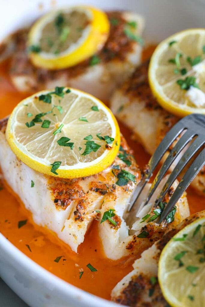 close up image of oven baked cod with lemon and parsley on top