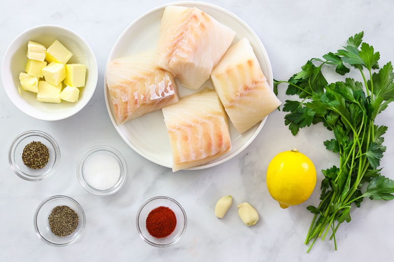 An overhead image of baked cod ingredients on a white background