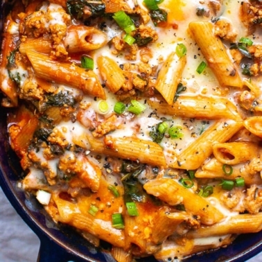 Ground turkey pasta bake garnished with green onion in a baking dish.