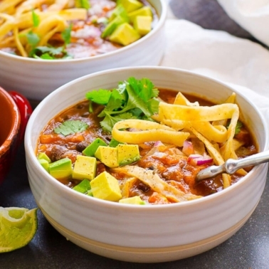 Instant Pot chicken tortilla soup garnished with tortilla strips, avocado and cilantro served in bowls.